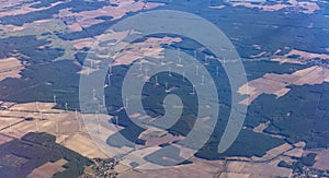 Wind power plant and agricultural fields from above. Aerial view out of an airplane window.