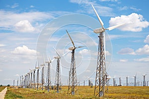 Wind power plant in the field. Wind power station on the horizon, against a beautiful blue sky with clouds. Industry,