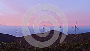 Wind power plant on mountain near sea at dawn