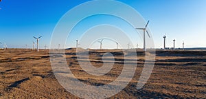 Wind power plants in desert at sunset