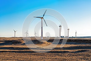 Wind power plants in desert at sunset
