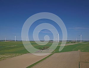 Wind power station in the daytime in the spring. Rotating blades of energy generators. Ecologically clean electricity. Modern tech