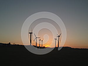 Wind power station in the sunset. Rotating blades of energy generators. Ecologically clean electricity. Modern technologies for t photo