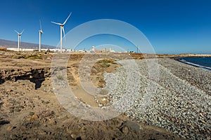 Wind power stations. A row of turbines near the seashore. Wind farm eco field. Eolic park with blue sky in background. Green,