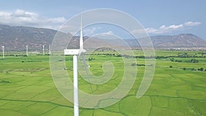 Wind power turbine on blue sky and mountain landscape drone view. Wind generator for clean renewable energy aerial view