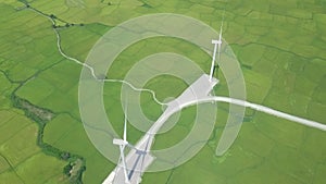 Wind power turbines on green agricultural field drone view. Wind generator on energy station aerial view. Windmill