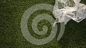 Wind rolling plastic packing on grass, dangerous responsibility towards earth