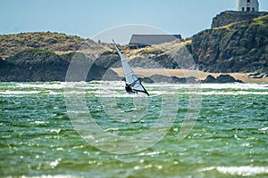 Wind surfer enjoys the beach at Newborough Warren with the Island of Llanddwyn in the background , Isle of Anglesey