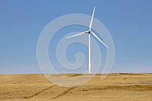 A wind tower turbine electricity generator, renewable energy source on a farm field.