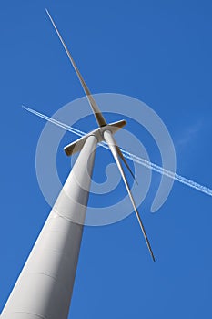 Wind Turbine and Aeroplane Vapour Trail Against a Blue Sky