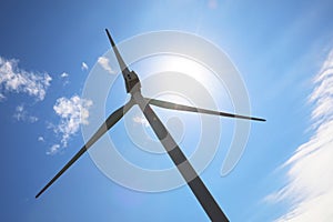 Wind turbine against blue sky, low angle view. Alternative energy source