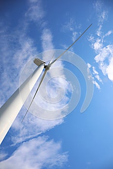 Wind turbine against blue sky, low angle view. Alternative energy source