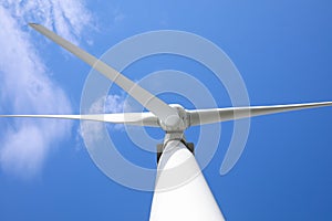 Wind turbine against blue sky, low angle view. Alternative energy source