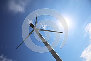 Wind turbine against blue sky, low angle view. Alternative energy source