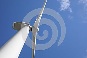 Wind turbine against blue sky, low angle view. Alternative energy source