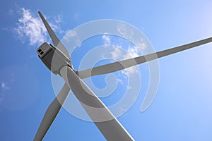 Wind turbine against blue sky, low angle view. Alternative energy source