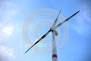 Wind turbine against blue sky, low angle view. Alternative energy source