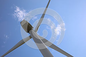 Wind turbine against blue sky, low angle view. Alternative energy source