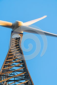 Wind turbine against a clear blue sky. Metal structure with struts and rivets at a wind turbine farm on a sunny day.