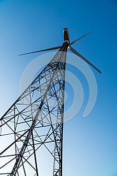 Wind turbine against a clear blue sky. Theme of renewable energy clean power generation and sustainable energy concepts.