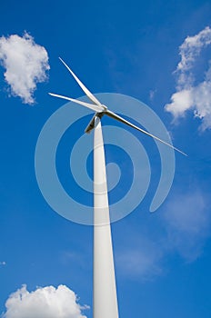 Wind turbine against cloudy blue sky