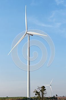 Wind turbine against cloudy blue sky background