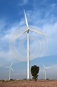 Wind turbine against cloudy blue sky background