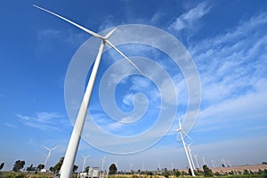 Wind turbine against cloudy blue sky background