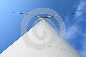 Wind turbine against cloudy blue sky background