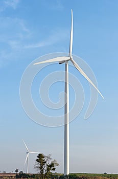 Wind turbine against cloudy blue sky background