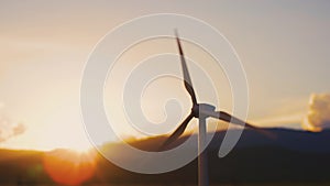 Wind turbine with blades turn on nature background with sunset sky