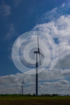 Wind turbine on a bright sunny day against the backdrop of a cloudy sky