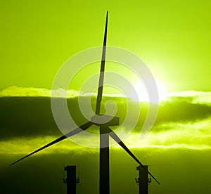 Wind turbine and chimneys of power plant at sunrise