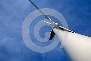Wind turbine close up looking up with bright blue sky