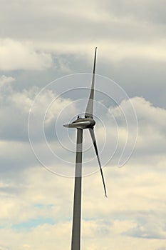 Wind turbine on a cloudy sky background