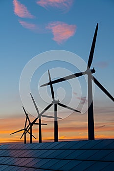 Wind turbine energy generaters on wind farm at sunset