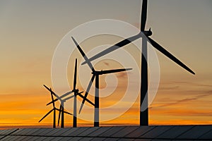 Wind turbine energy generaters on wind farm at sunset