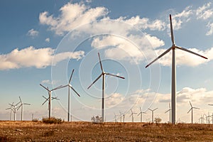 Wind turbine farm over the blue clouded sky