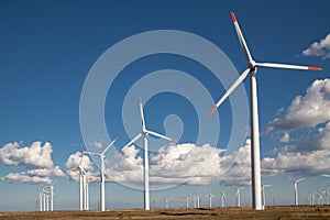 Wind turbine farm over blue clouded sky