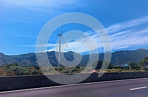 A wind turbine field with an asphalt road foreground