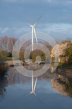 wind turbine in the field reflecting in a canal in the UK