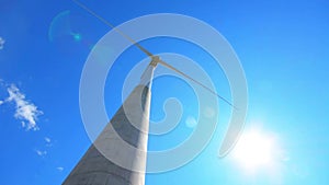 Wind turbine generating electricity on blue sky. Low angle view.