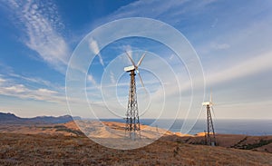 Wind turbine generating electricity in mountains at sunset