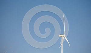 Wind turbine generating electricity over blue sky