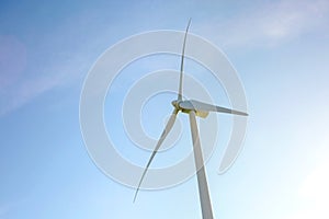 Wind turbine generating electricity over blue sky background