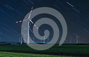 Wind turbine on green fields at night. Natural wind power plants and sustainable eco-friendly energy