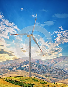 Wind turbine on a hill against the sunset sky