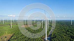 Wind turbine near green forest, beautiful aerial landscape with blue sky. Alternative energy concept.
