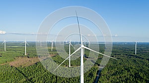 Wind turbine near green forest, beautiful aerial landscape with blue sky. Producing energy in environmentally friendly way. close