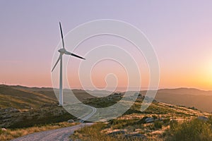 Wind turbine with offroad trail and vibrant sunset photo